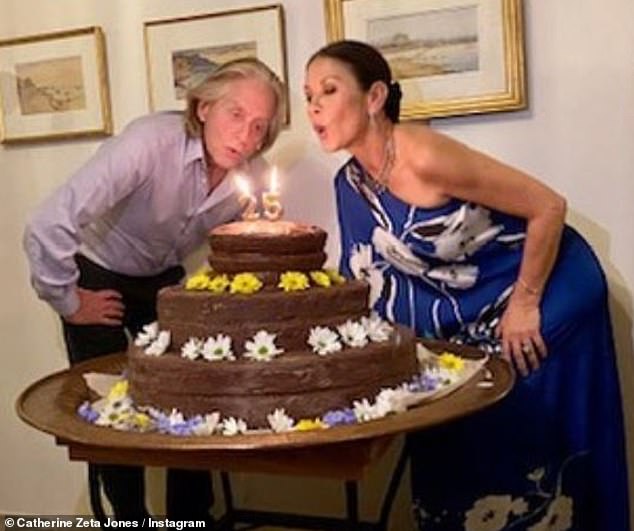 Big day: Michael Douglas proved he still had a lot of breath when he blew out his candles on a joint birthday cake alongside his wife Catherine Zeta Jones